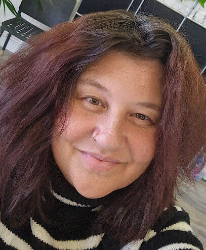 Eine Frau mit einem schwarz-weiss gestreiften Pullover schaut in die Kamera.