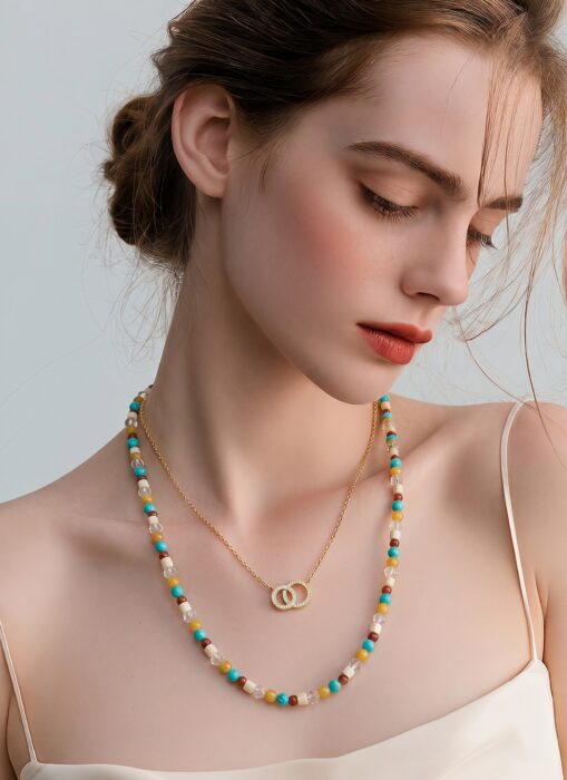 Editoriales Schmuckportrait mit farbigem Layering-Look und feinen Golddetails.